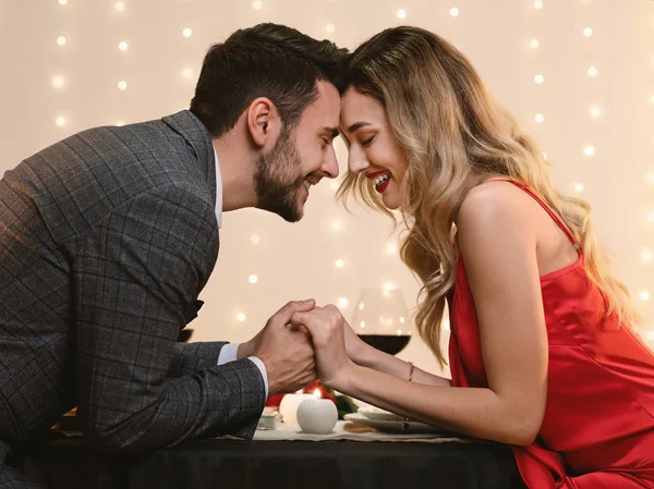 Doce casal apaixonado de mãos dadas durante o jantar romântico no restaurante — Fotografia de Stock