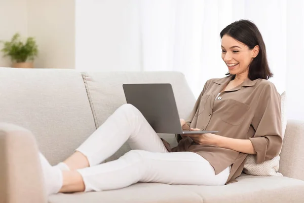 Young girl working on laptop online at couch — 스톡 사진