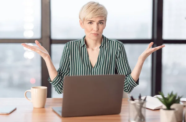 Загадочная предпринимательница на Laptop Gesturing сидит в современном офисе — стоковое фото