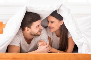 Sevgi dolu bir çift evde battaniyeyle yatarak konuşuyor.