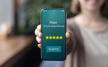 Gülümseyen kadın, 5 yıldızlı modern telefonu tutuyor.