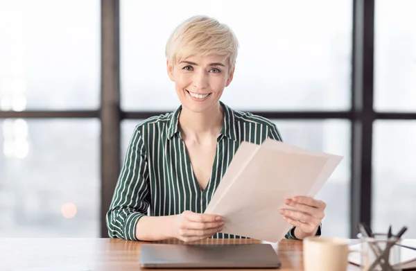 Fröhliche Geschäftsfrau mit Dokumenten am Laptop in modernem Büro — Stockfoto