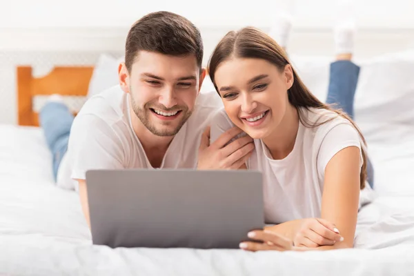 Novio y novia acostado con el ordenador portátil viendo película en el dormitorio —  Fotos de Stock