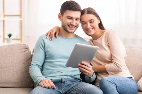 Cônjuges usando tablet digital sentado no sofá em casa — Fotografia de Stock