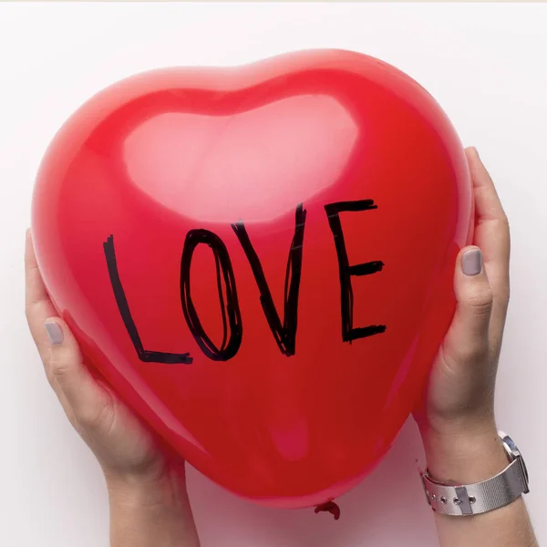 Woman holding heart shape balloon with text love over white — 스톡 사진