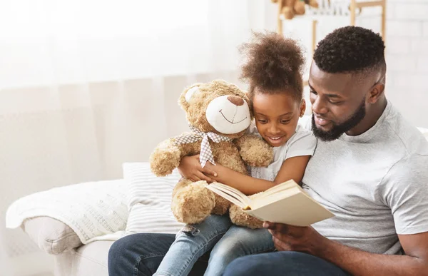 Lindo afro familia padre e hija lectura libro en casa —  Fotos de Stock