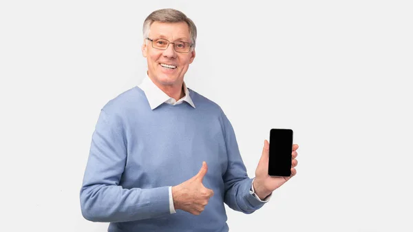 Äldre man visar telefonen Blank Screen Gesturing Tummen upp, Grå bakgrund — Stockfoto