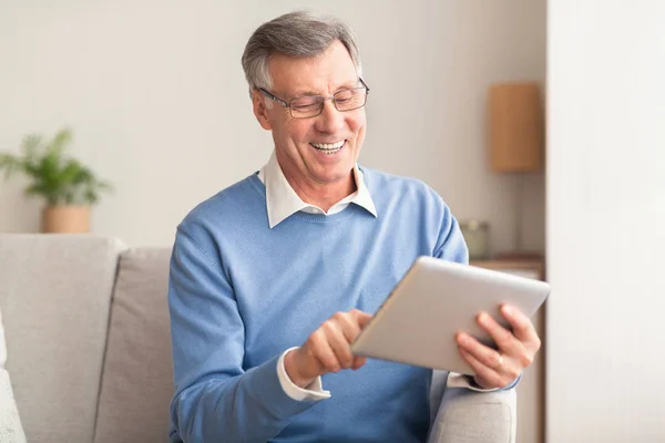 Senior Man with Tablet Computer Browsing Internet Κάθεται στον καναπέ — Φωτογραφία Αρχείου