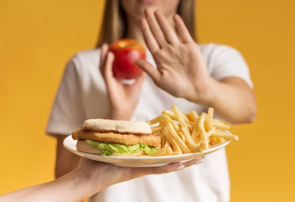 Donna che rifiuta piatto con cibo malsano e la scelta di mela — Foto Stock