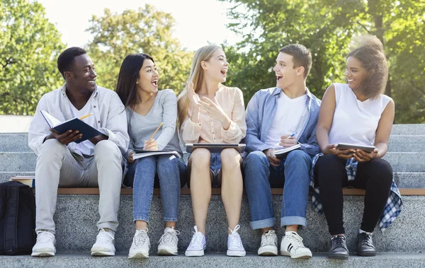 Radosni studenci studiują i rozmawiają, siedzą w mieście — Zdjęcie stockowe