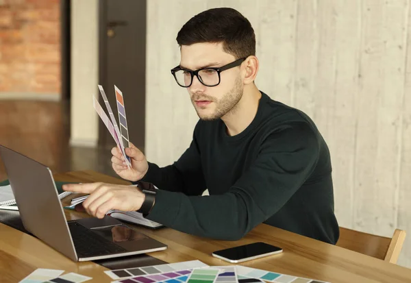 Σχεδιαστής Freelancer που εργάζονται σε φορητό υπολογιστή Επιλέγοντας δείγματα χρώματος στο γραφείο — Φωτογραφία Αρχείου