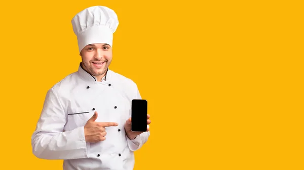Teléfono de retención de chef positivo con pantalla en blanco sobre fondo amarillo — Foto de Stock
