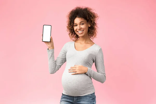 Aplikasi keren. Wanita hamil yang bahagia menampilkan telepon dengan layar kosong — Stok Foto