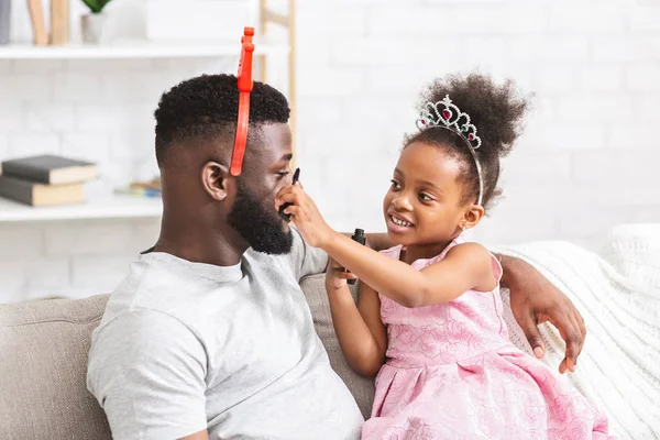 Verspieltes schwarzes Mädchen, das ihrem Vater Wimpern mit Wimperntusche aufsetzt — Stockfoto