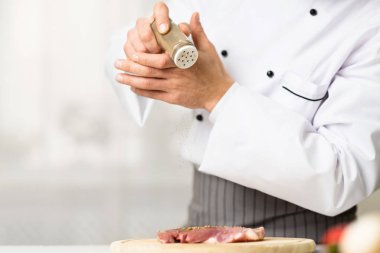 Unrecognizable Male Chef Cooking And Seasoning Meat Steak In Kitchen