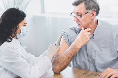 Mexican doctor doing vaccination to elderly man
