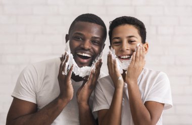 Mutlu Afro babalar ve tıraş köpüklü oğlu.