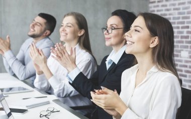 Neşeli iş arkadaşları toplantının ardından el çırpıyorlar.