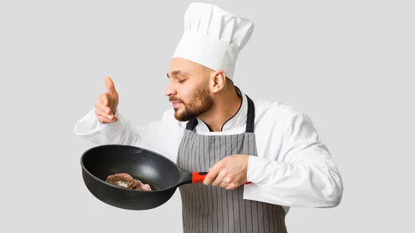 Chef cheirando frigideira com bife fresco, fundo cinza, Panorama — Fotografia de Stock