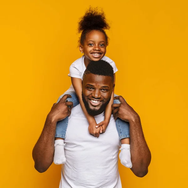 Vrolijk portret van zwarte vader en dochter over gele achtergrond — Stockfoto
