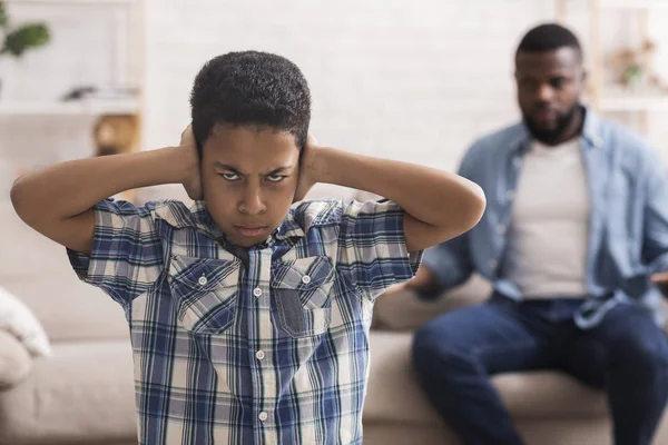 Preteen black boy closing ears not to listen fathers scolding