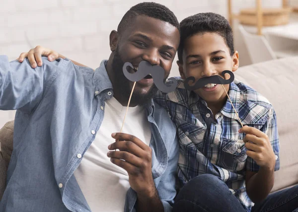 Preto pai e filho tomando selfie, segurando bigode falso em paus — Fotografia de Stock