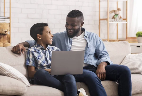 Afro pai e filho usando laptop em casa — Fotografia de Stock