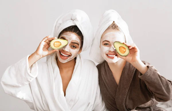 Novia en albornoces y mascarillas cubriendo los ojos con aguacate — Foto de Stock