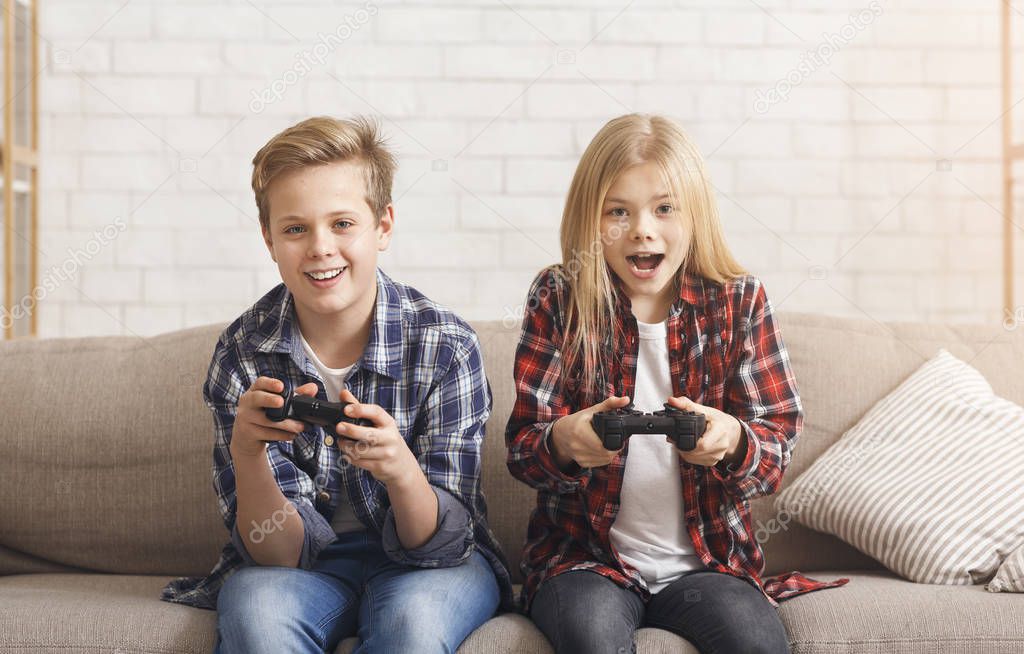 Cute Brother And Sister Playing Video Game Sitting On Couch
