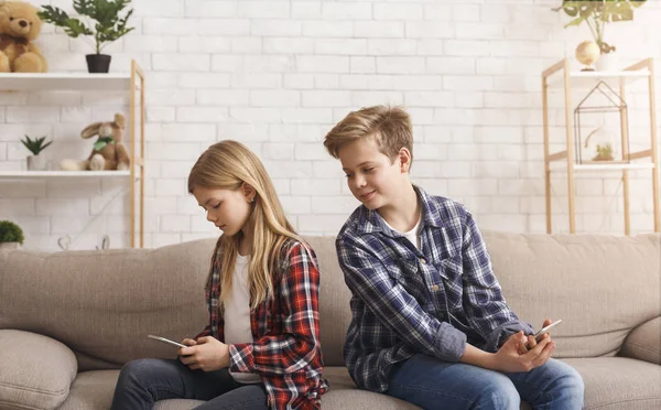 Neugieriger Bruder liest Schwester Nachrichten am Telefon auf Couch — Stockfoto