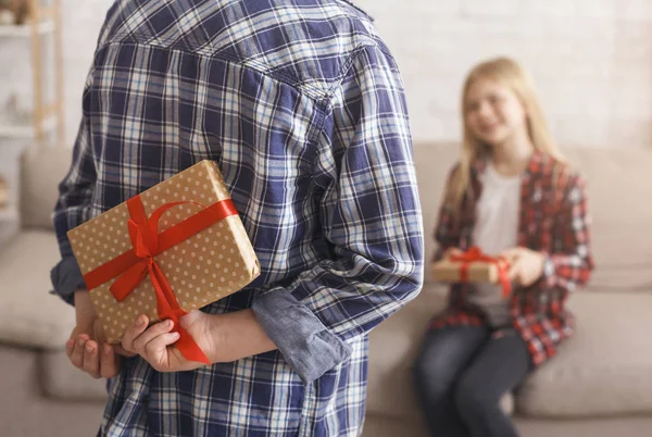 Unrecognizable Boy Holding Gift Congratulting Girl Sitting On Couch Indoor