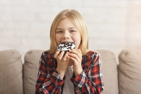 Girl Enjoying Eating Unhealthy Donut Sitting On Sofa At Home