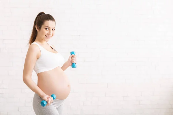 Wanita hamil berolahraga dengan dumbbells di rumah — Stok Foto