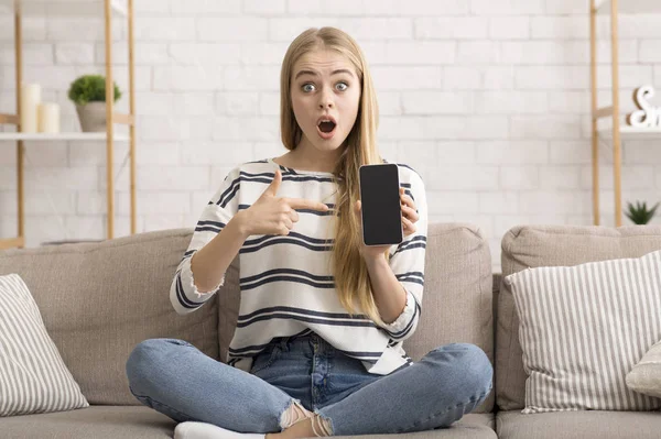 Surprised pretty girl pointing at blank smartphone screen — Stock Photo, Image
