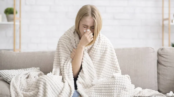 Jovem ficou doente, envolto em cobertor soprando nariz — Fotografia de Stock