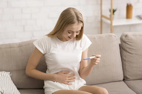 Izgalmas lány pizsamában pozitív terhességi tesztet tart — Stock Fotó
