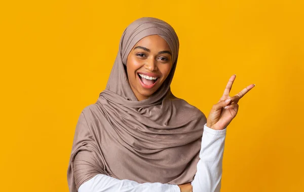 Χαρούμενη αφρο-μουσουλμάνα κοπέλα με μαντίλα που χαιδεύει την ειρήνη, που δείχνει το σύμβολο του v — Φωτογραφία Αρχείου