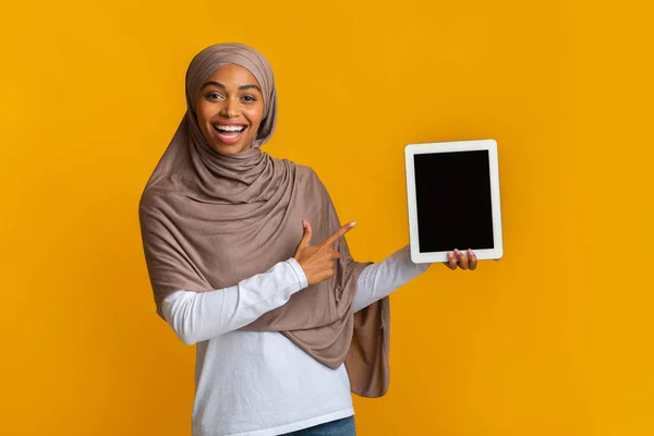 Χαρούμενη μαύρη μουσουλμάνα γυναίκα που δείχνει σε ψηφιακή πλακέτα με μαύρη οθόνη — Φωτογραφία Αρχείου