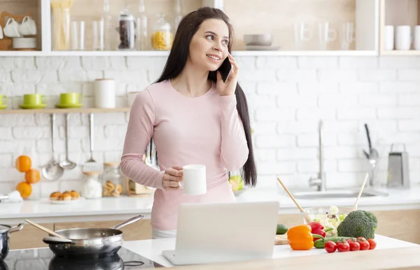 Jonge vrouw koken en chatten op mobiele telefoon — Stockfoto