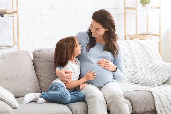 Terhes nő és kislánya otthon beszélgetnek. — Stock Fotó