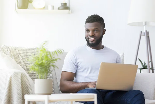 Pozitív fekete férfi gépel laptopon otthon — Stock Fotó