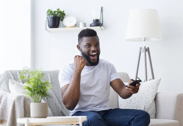 Känslomässig afrikansk kille tittar på sport på tv — Stockfoto