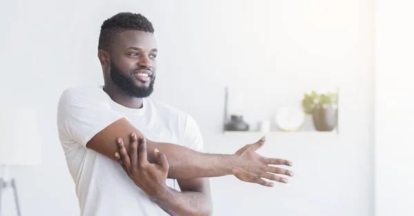 Pria Afrika ceria pemanasan, peregangan tangan di rumah — Stok Foto