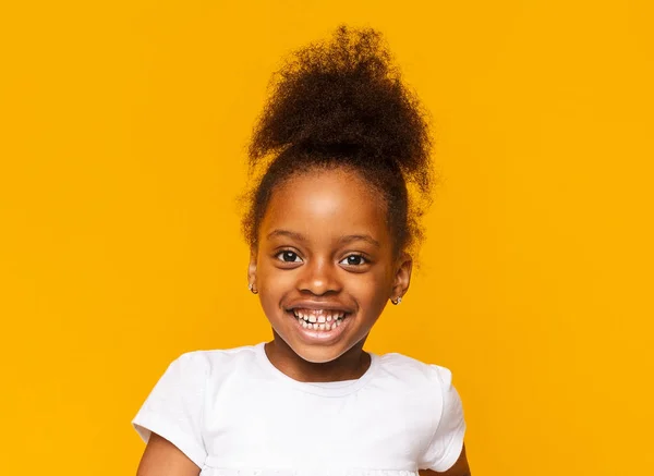 Portrait of african little girl smiling over yellow background — Stock Photo, Image