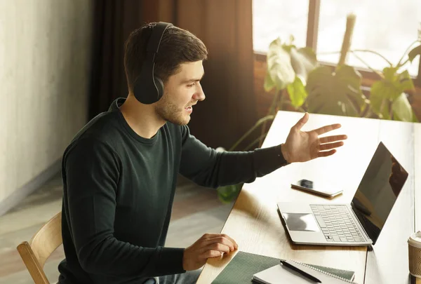 Mężczyzna w słuchawkach podejmowania rozmowy wideo siedzi w nowoczesnym biurze — Zdjęcie stockowe