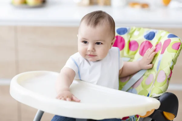 Симпатичный ребенок, сидящий в стульчике на кухне — стоковое фото