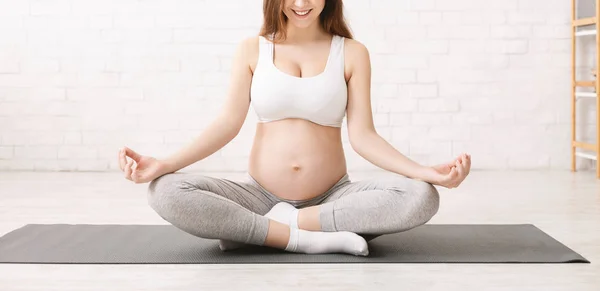 Mulher grávida ativa meditando na posição de lótus em casa — Fotografia de Stock