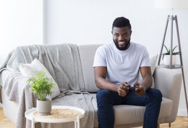 Yetişkin Afrikalı adam evde video oyunu oynuyor.