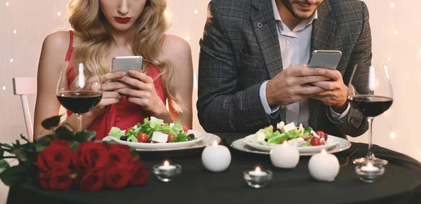 Férfiak és nők beragadva az okostelefonjaikba randin az étteremben — Stock Fotó