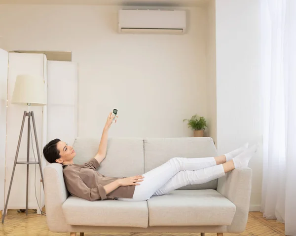 Jovem mulher ligando ar condicionado em sua casa — Fotografia de Stock